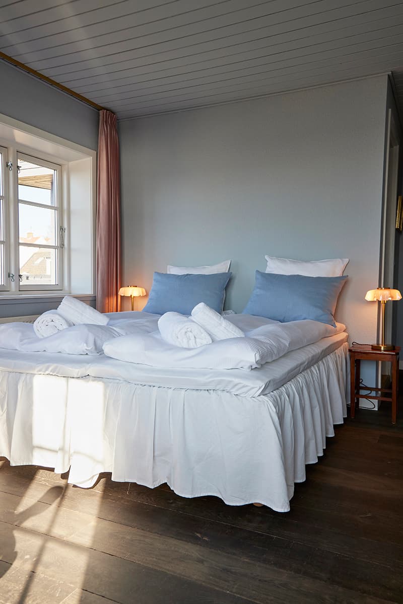 Nye senge og natborde med antikke lamper på dobbeltværelse Hotel Kysten Bornholm