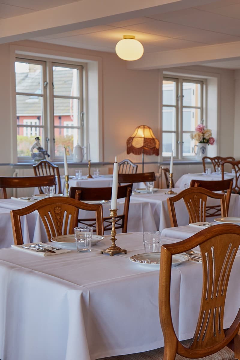 Restaurant Kysten dækket op til gæster med hvide duge lys og klassiske møbler